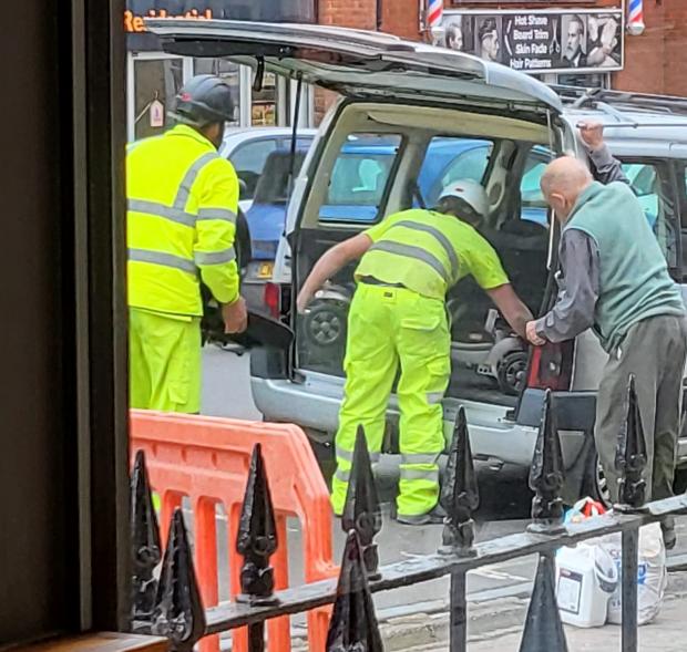 Chard & Ilminster News: Two men in high-visibility jackets help a man lift his mobility scooter into his car. Picture: Nicole Hooper