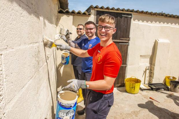 Chard & Ilminster News: WPD apprentices paint the side of the barn during its renovation. Picture: Western Power Distribution